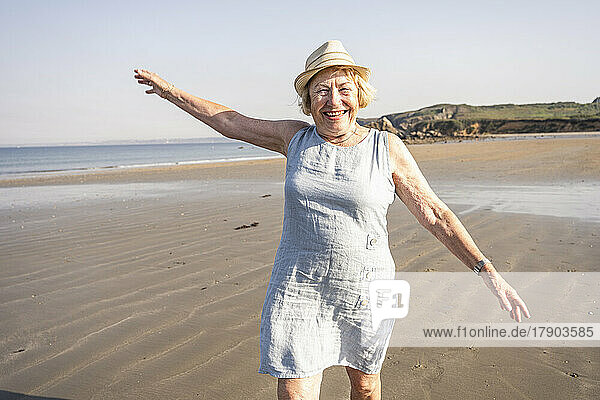 Happy woman with arms raised enjoying vacation at beach
