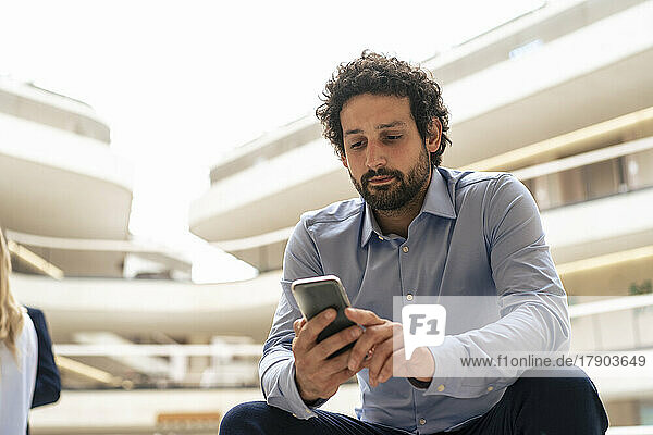 Businessman text messaging through mobile phone in office