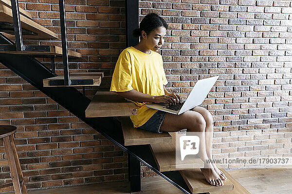 Woman working on a computer sitting on stairs