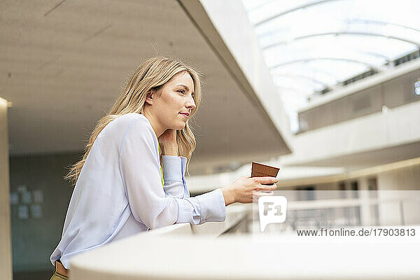 Thoughtful businesswoman with coffee cup in corridor