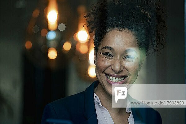 Cheerful businesswoman seen through glass at workplace