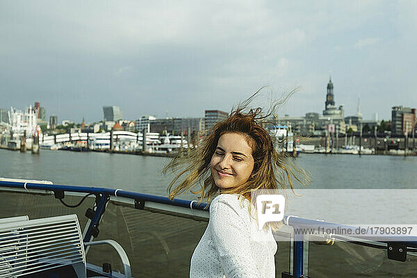 Smiling woman with eyes closed sitting in ferry boat on sunny day  Hamburg  Germany