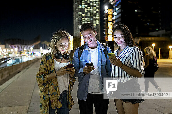 Smiling man and women surfing net through smart phone in city
