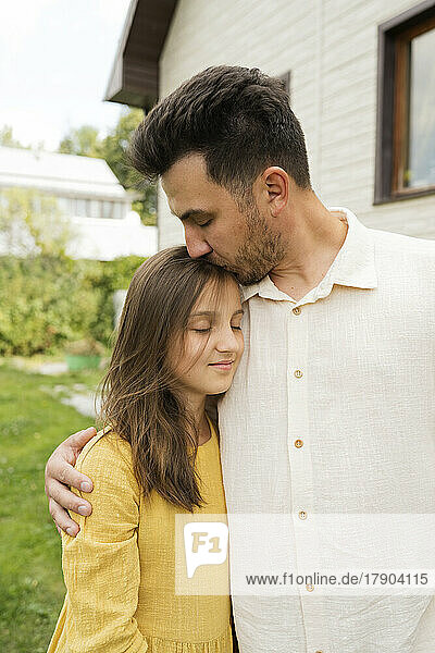 Zärtlicher Vater küsst Tochter mit geschlossenen Augen im Hinterhof