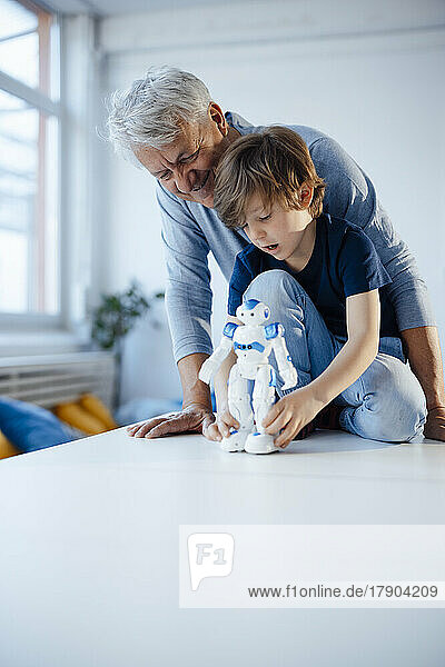 Boy with robot model by smiling grandfather at home