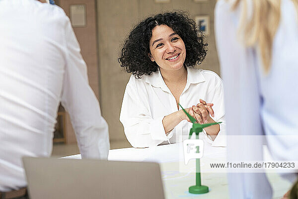Smiling businesswoman discussing over wind turbine model with colleagues