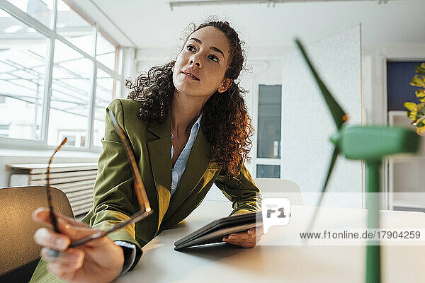 Businesswoman with tablet PC sitting at desk in office