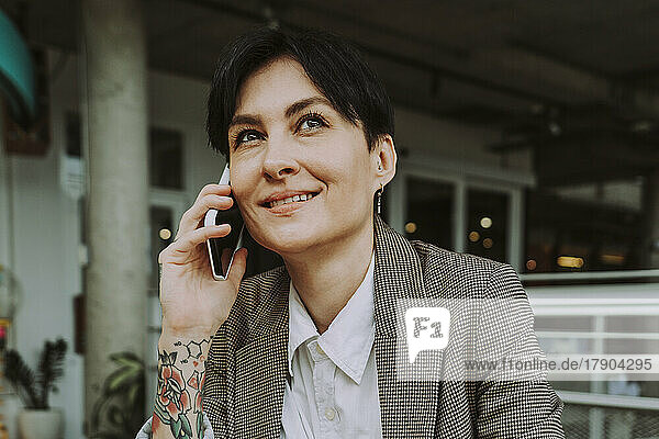 Smiling businesswoman talking on smart phone in cafe