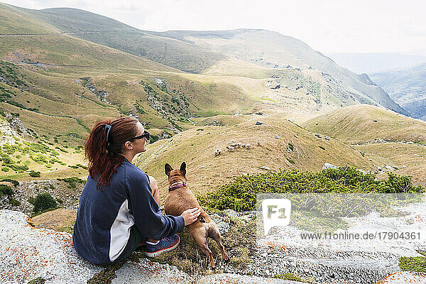 Woman with dog sitting in front of mountain