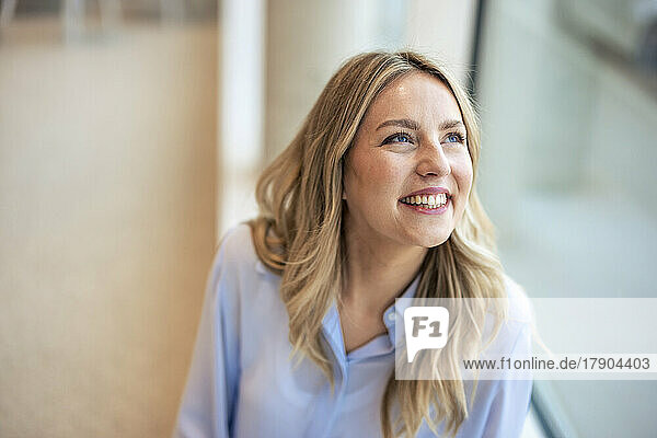 Happy businesswoman looking up in office