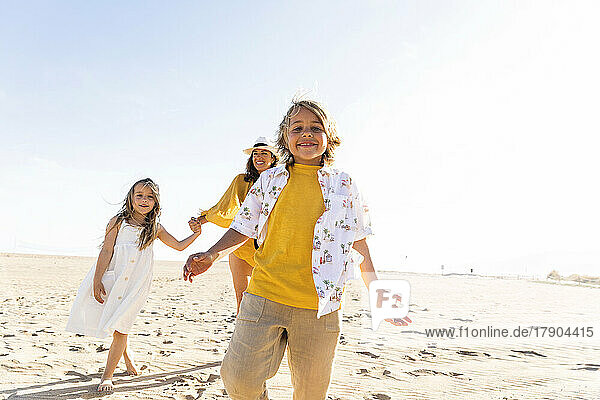 Happy boy with sister and mother having fun at beach on sunny day