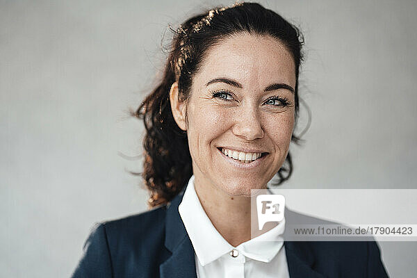 Smiling businesswoman in front of gray wall