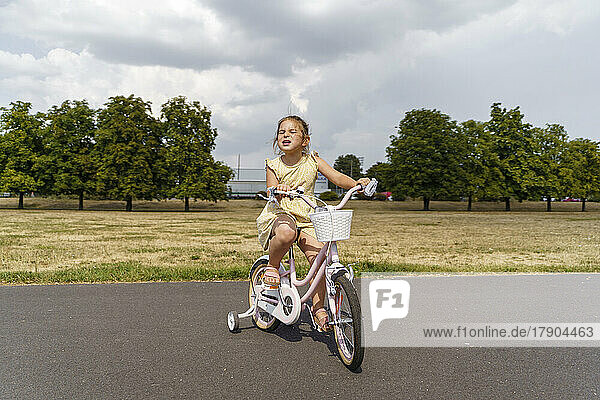 Girl cycling on road at park