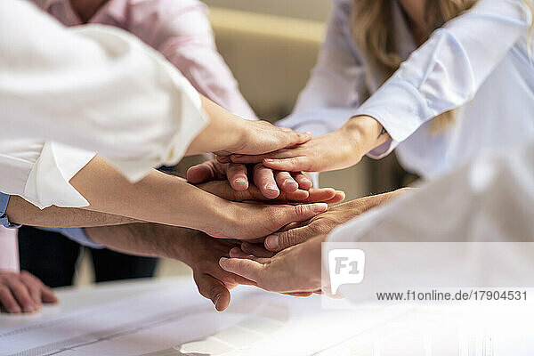 Hands of business colleagues stacking hands in office