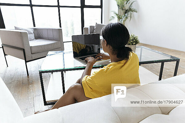 Woman sitting in living room working from home using laptop