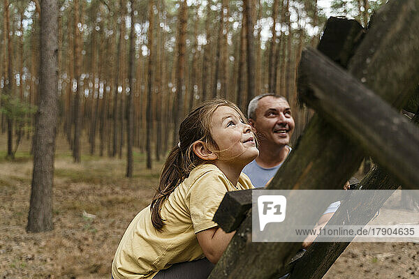 Smiling girl climbing ladder in forest