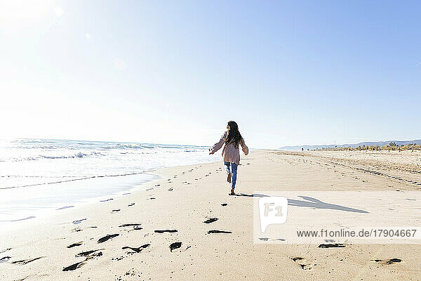 Mädchen hat Spaß beim Laufen am Strand an einem sonnigen Tag