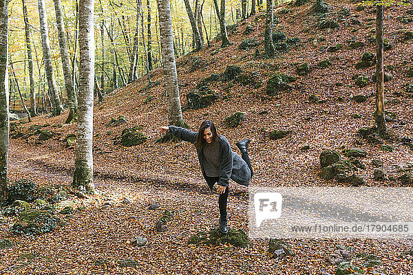 Smiling woman balancing on rock at Fageda D'en Jorda  Olot  Girona  Spain
