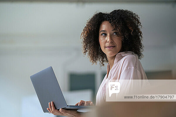 Contemplative businesswoman with laptop in office