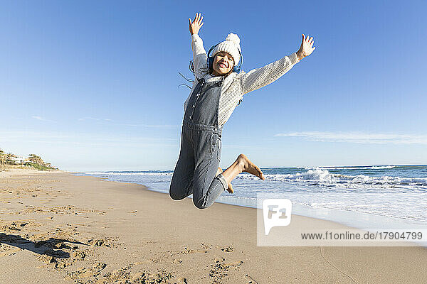 Fröhliches Mädchen springt am Strand in die Luft