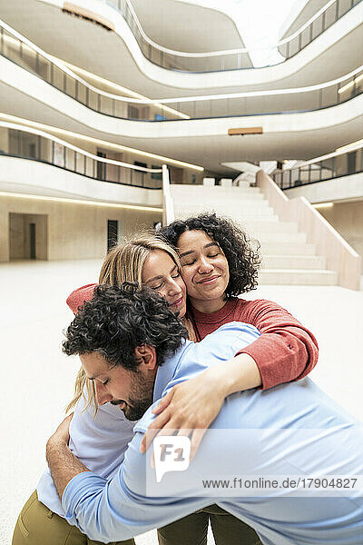 Multiracial business colleagues embracing each other in lobby