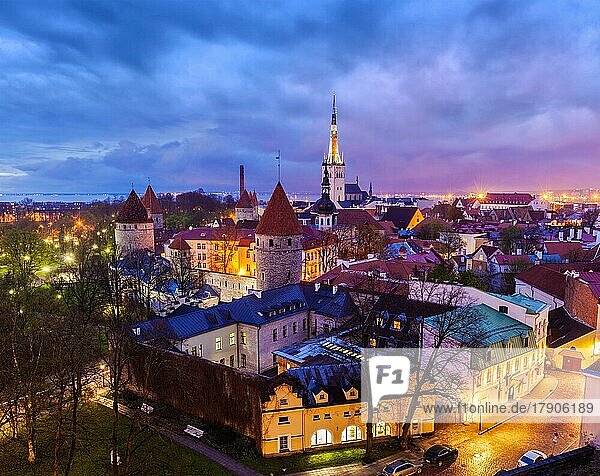 Luftaufnahme der mittelalterlichen Altstadt von Tallinn mit der St. -Olaf-Kirche und der abendlich beleuchteten Stadtmauer von Tallinn mit dramatischer Wolkenlandschaft  Estland  Europa