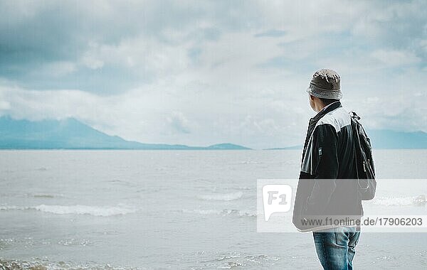 Rückansicht eines Touristen mit Blick auf einen See mit Vulkanen. Explorer Person mit Blick auf einen See an einem sonnigen Tag. Tourist Mann in Hut von hinten Blick auf einen See mit Vulkanen in Rivas  Nicaragua  Mittelamerika