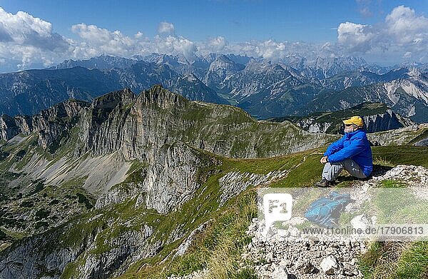 Mountain hiker resting at the summit of Hochiss and enjoying the view of Dalfazkamm and Karwendel Mountains  Hochiss  Rofan Mountains  Tyrol  Austria  Europe