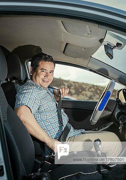 Glücklicher Fahrer beim Anlegen des Sicherheitsgurtes  Lächelnder männlicher Fahrer beim Anlegen des Sicherheitsgurtes. Konzept eines Fahrers in seinem Auto  der sich anschnallt. Lächelnde Person beim Anlegen des Sicherheitsgurtes