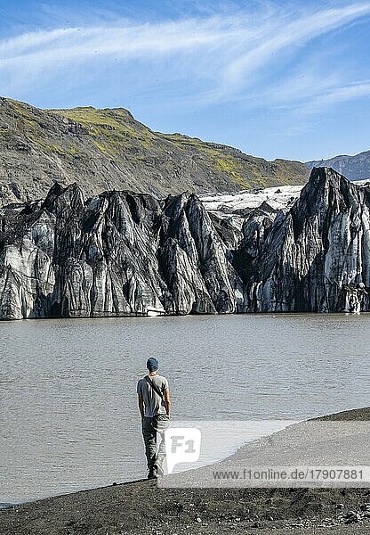 Tourist at the lakeside of a glacier lagoon  glacier tongue with crevasses and lake  Sólheimajökull  South Iceland  Iceland  Europe