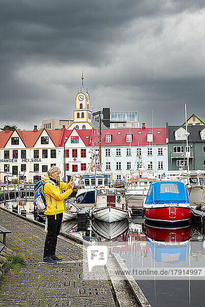 Ein Tourist macht ein Foto mit einem Smartphone vom Pier des Hafens von Torshavn  Insel Streymoy  Färöer Inseln  Dänemark  Europa