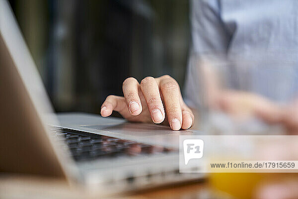 Close-up shot of woman's hand typing on laptop computer at outdoors office