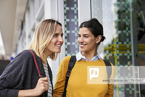 Mid-shot of two female friends taking a walk outdoors while window shopping