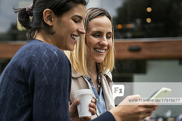 Mid-shot Seitenansicht von zwei Unternehmerinnen  die Nachrichten von ihren Followern auf ihren Smartphones überprüfen