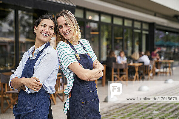 Porträt von zwei glücklichen Restaurantbesitzerinnen  die vor ihrem Restaurant posieren und Spaß haben