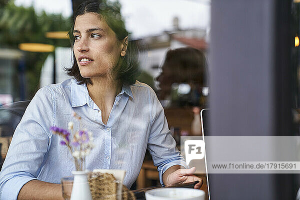 Porträtaufnahme durch das Fenster einer lateinamerikanischen Frau  die in einem Café sitzt