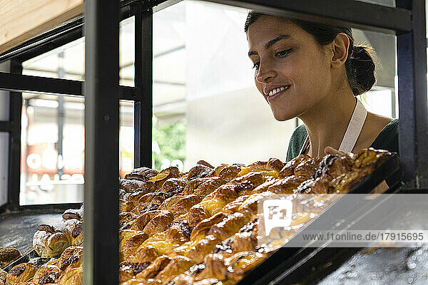Mittlere Einstellung einer lateinamerikanischen Bäckereibesitzerin  die ihr Gebäck in einem Regal betrachtet