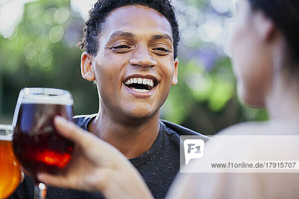 Fröhlicher lateinamerikanischer Mann  der sich beim Biertrinken mit Freunden amüsiert