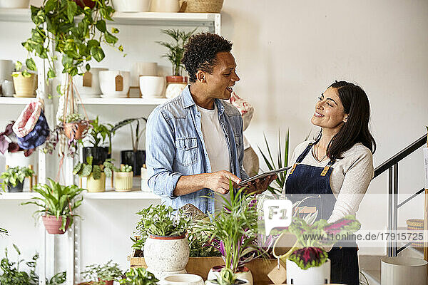 Latin American male gardener discussing over digital tablet with female coworker