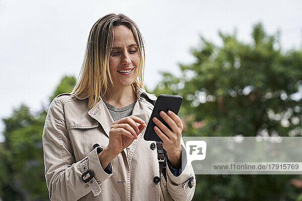 Attraktive Frau schaut auf ihr Handy  während sie auf der Straße geht
