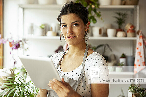 Young adult female nursery worker holding digital tablet