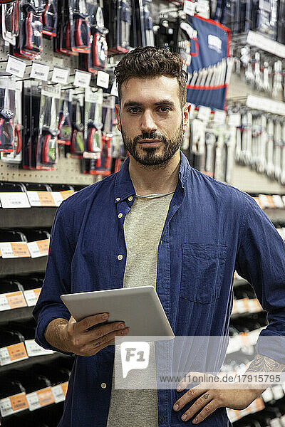 Hardware shop owner looking at the camera while holding digital tablet