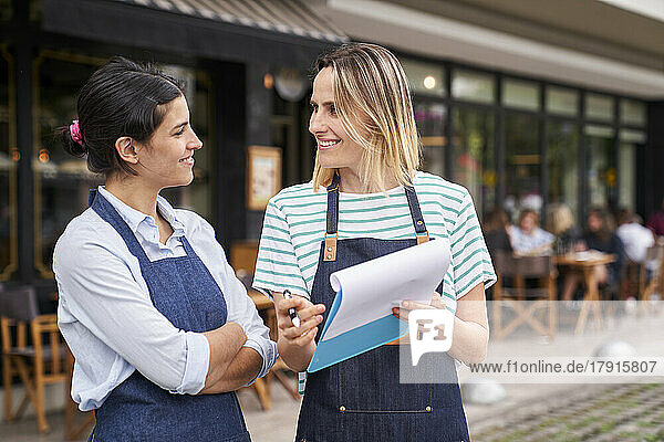 Mid-shot of two female restaurant owners checking a list outside their restaurant