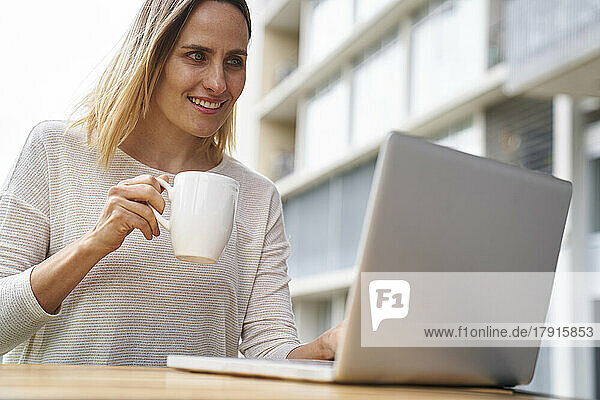 Niedriger Blickwinkel auf eine Unternehmerin  die auf einen Laptop-Bildschirm schaut und Kaffee trinkt