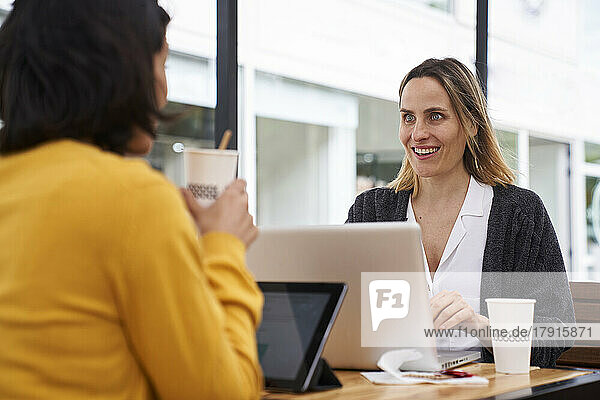 Mittlere Einstellung von zwei weiblichen Mitarbeitern  die sich in einem Büro im Freien über geschäftliche Themen unterhalten