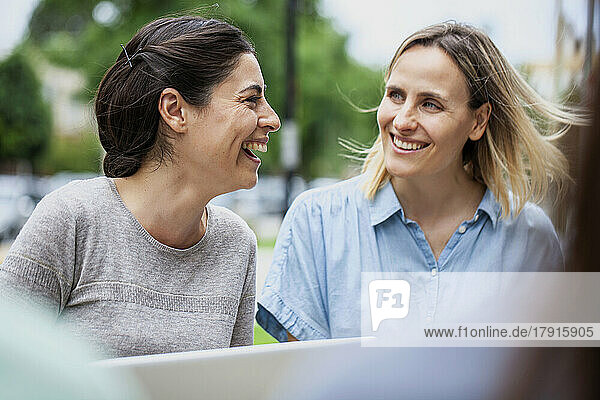 Female coworkers laughing while sitting outdoors