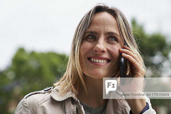 Nahaufnahme einer lächelnden Frau  die auf der Straße mit einem Handy telefoniert