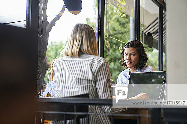 Mid-shot von zwei Unternehmerinnen  die sich in einem Café über ihr Geschäft unterhalten
