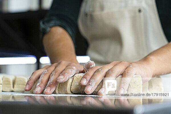 Niedriger Blickwinkel auf die Hände einer Bäckerin beim Kneten von Gebäck