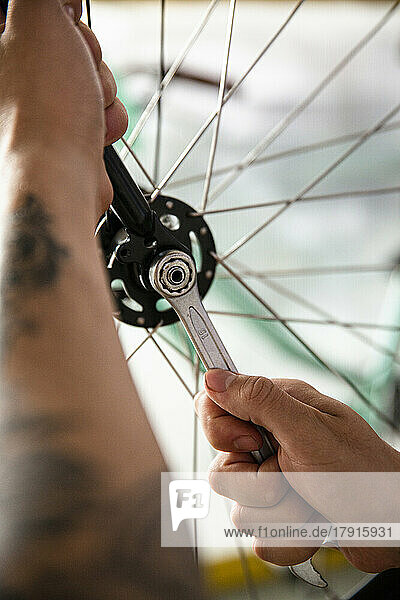 Close-up of bicycle mechanic adjusting wheel with wrench